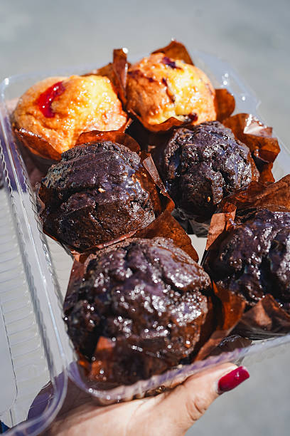 Hand holding container of fresh chocolate and berry muffins