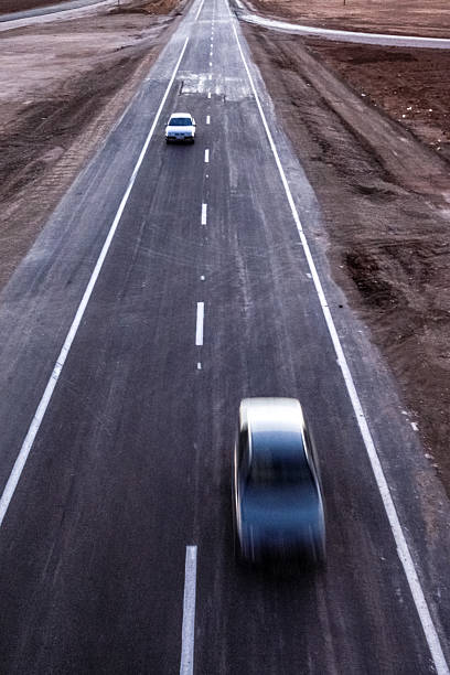 A car is swiftly moving on a fall country road. In the background, two cars are getting ready to overtake. Blurred environment. Hungary