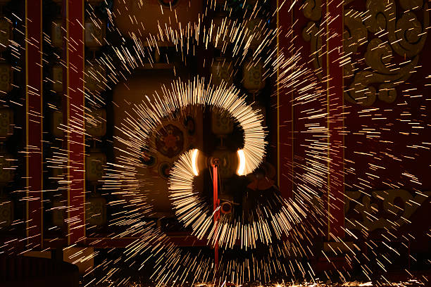 This image captures a stunning fire spinning performance, showcasing luminous circles and swirling patterns against a stark black