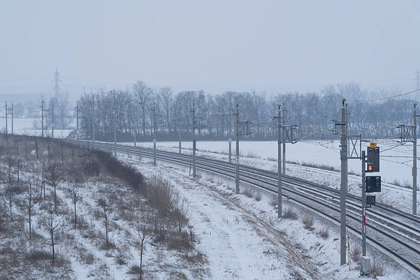 cold icy winter day in rural landscape with railway tracks and overhead lines, weather and snow causing many delays in puplic transport