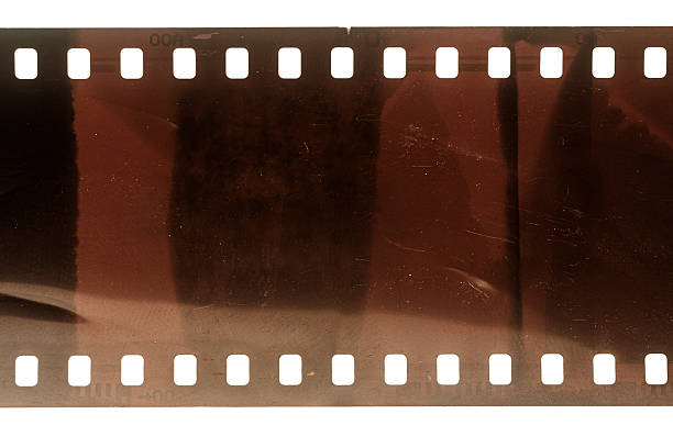 Dusty and grungy 35mm film texture or surface. Perforated scratched camera film isolated on white background.