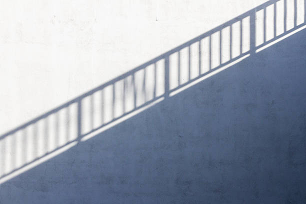 Yellow bridge railing and a shadow of it on concrete wall. Architectural detail.