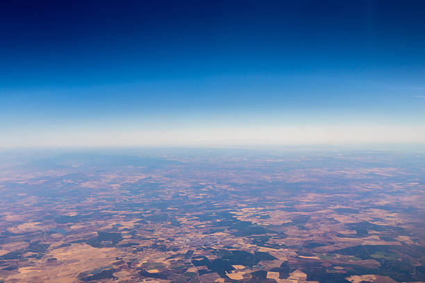 A passenger view from high above the earth's surface as an aircraft flies across the landscape.