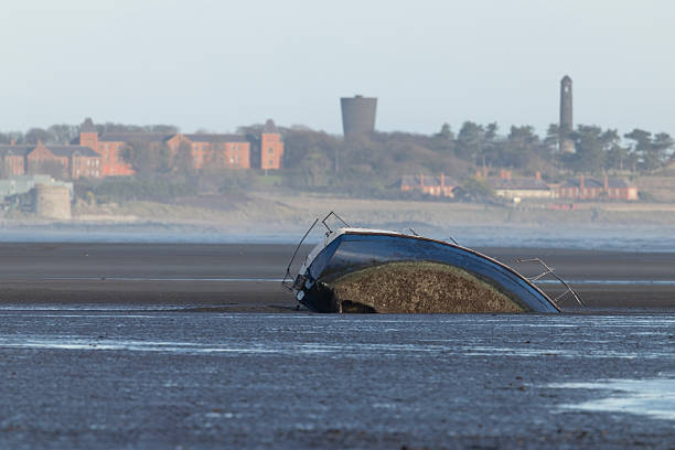 An image of a sunken boat in the sand at Malahide Dublin with Donabate in the distance