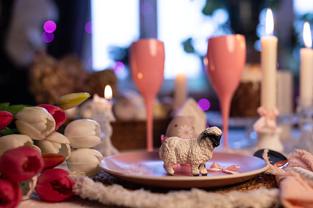 Festive Easter table setting with candles, pastel glasses, cakes and decorative eggs.