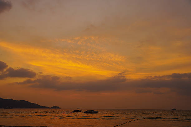 Colorful sunset sky over a tropical beach, blending warm hues with distant shoreline