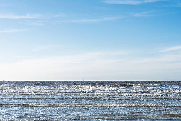 Experience the calming rhythm of gentle ocean waves on the shore. This serene image captures the beauty of the sea and sky, perfect for evoking relaxation and ideal for various projects.