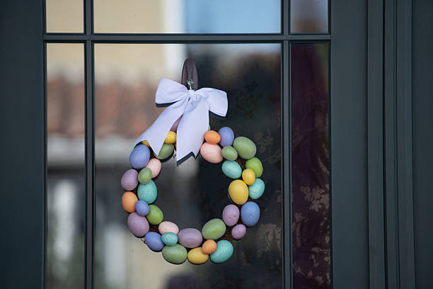 A detailed close-up of brightly colored Easter eggs hanging from a tree branch, illuminated by sunlight. The festive decorations, featuring various shades and patterns, create a joyful and vibrant atmosphere. The blurred background enhances the depth, making the eggs stand out beautifully.