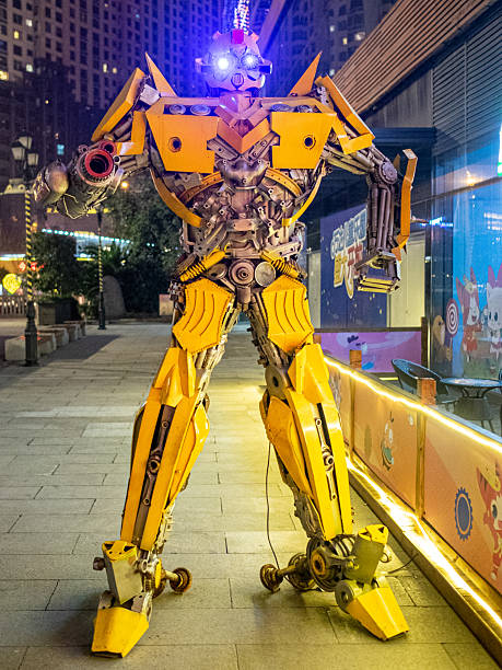 Wuhan, China - February 04, 2016: A large yellow model statue of the Transformer character Bumblebee standing on a pedestrian street in the Wanda commercial district at night, illuminated by city lights.