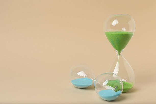 Hourglass with flowing sand on beige background. Space for text