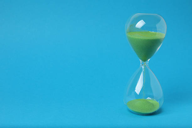 Hourglass with flowing sand on a blue background. Space for text