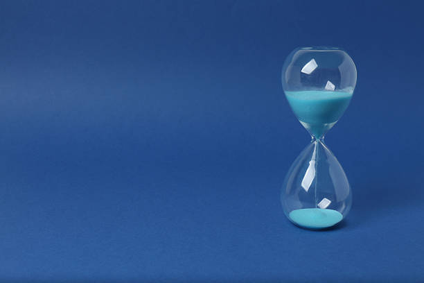 Hourglass with flowing sand on a blue background. Space for text