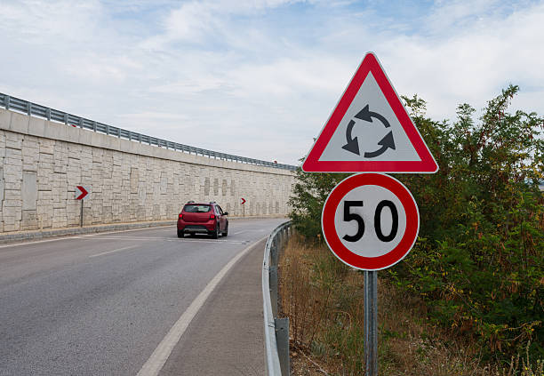 Roundabout warning road sign with 50 km/h speed limit on curved road