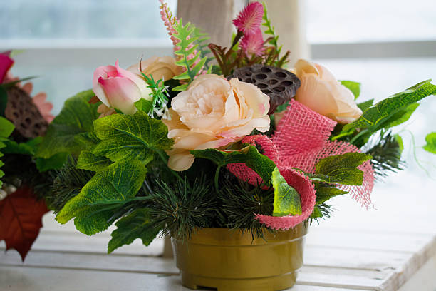 A composition of artificial flowers and greenery in a golden pot