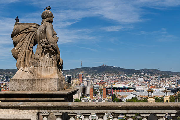 A back view of a classical sculpture sitting on a balustrade with a panoramic cityscape background.