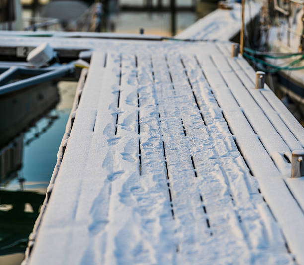 Snow covered wooden dock walkway in cold winter marina