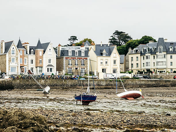 Sailboats rest on the tidal flats at low tide in front of historic waterfront houses in Saint-Malo, Brittany, reflecting everyday coastal life in northern France.