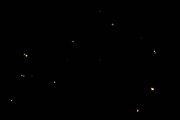 Abstract shot of tiny multi colored light particles and bokeh sparks scattered across a deep black night sky background. Perfect for creative overlays.