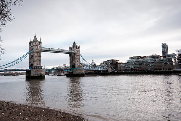 Iconic tower bridge spanning the river thames in london, united kingdom, featuring historic architecture and a modern city skyline under a neutral sky, symbolizing travel and landmark beauty