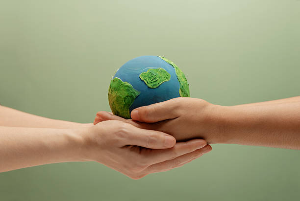 Two people holding globe together representing teamwork, shared responsibility, and environmental sustainability. Concept reflects collaboration, climate action, collective care, and protecting the planet