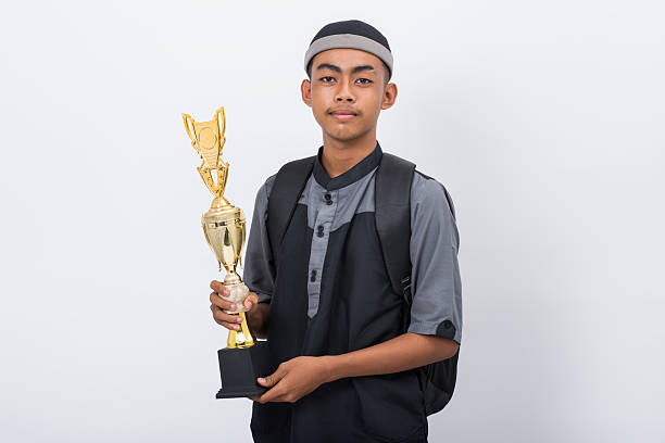 Young Madrasa student smiling holding a Trophy isolated on white background