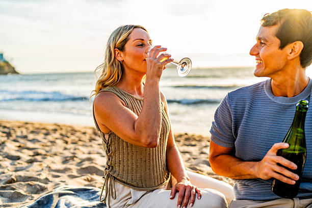 Couple talking and drinking wine during picnic on the beach