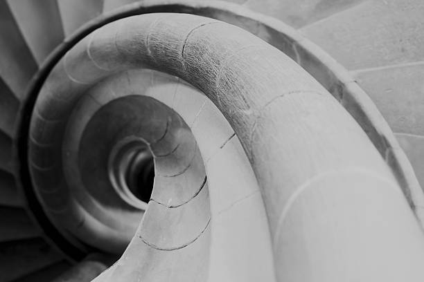 Close-up of a spiral staircase detail in black and white, highlighting curved architectural lines, texture, and geometric form.