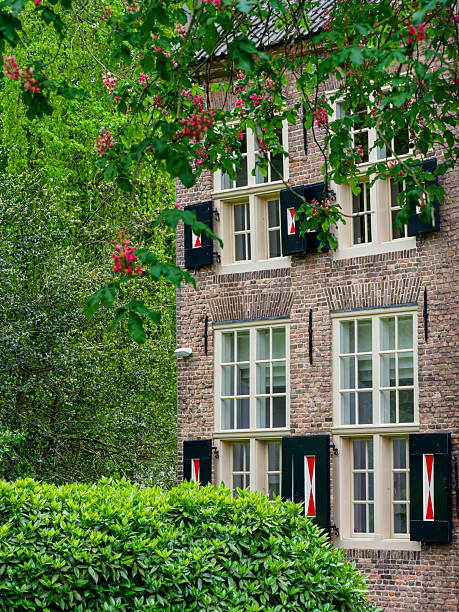 Traditional brick building in Tiel, Netherlands, featuring numerous windows with open green shutters and red and white details