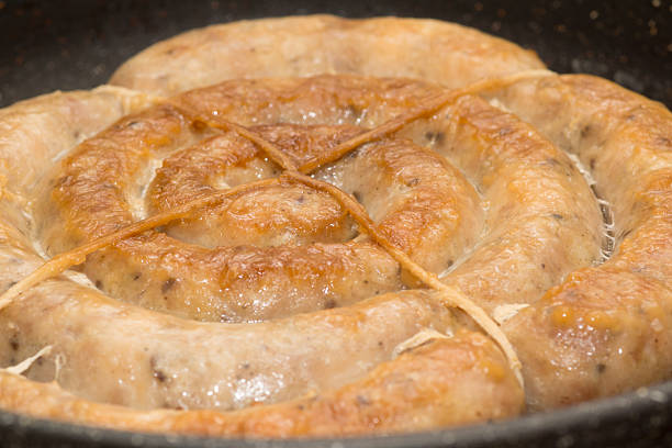 Delicious sausage tied with twine is fried in a frying pan