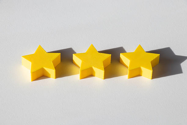 Three yellow 3D stars on a white background, hard side lighting, pronounced shadows, minimalist subject composition, symbol of appreciation, quality, and award