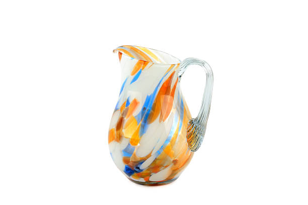 A vibrant hand-blown glass pitcher features striking orange and blue swirls against an opaque white base. This elegant artistic glassware is perfect for home decor or lifestyle concepts.