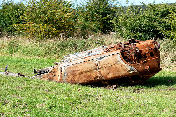 Stolen burnt rusty car abandoned on a meadow  in a countriside polluting the environment