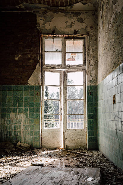 Antique door with windows by daylight and peeling paint in old building