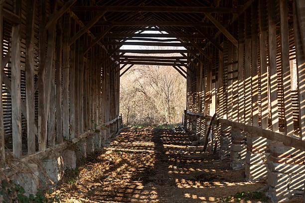 Tobacco barn sitting on a hill with snow covered path.