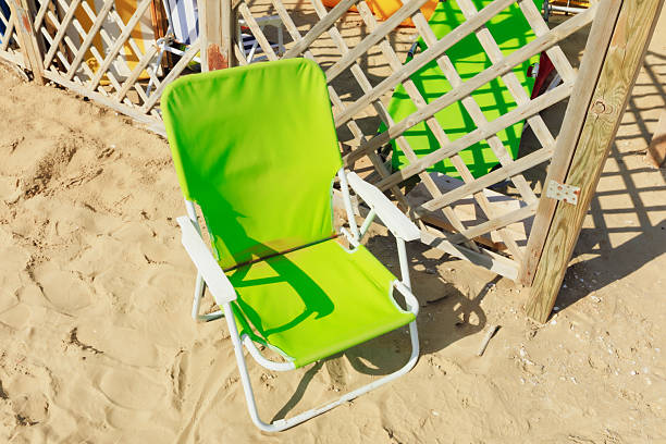 A peaceful coastal scene featuring two empty chairs placed on a sandy beach, facing the calm sea.