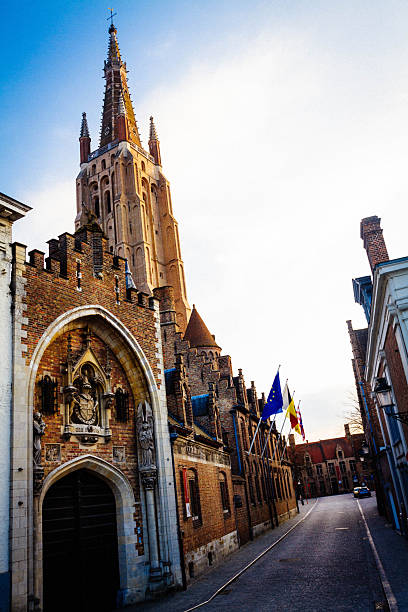 Empty street with historical church in Bruges with flags