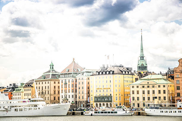 Stockholm, Sweden - June, 19, 2025:   Gamla Stan with multicolored houses and ships in the bay. Cloudy unpredictable weather