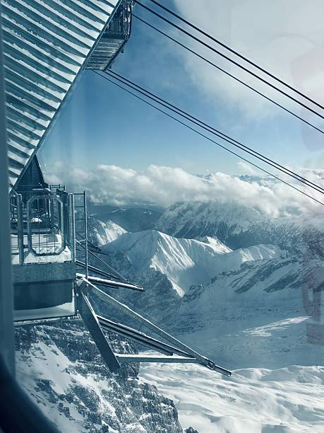Cable car and mountain infrastructure on Mount Zugspitze, the highest peak in Germany. Dramatic winter alpine landscape with snowy slopes, clouds and high-altitude scenery in Bavaria.