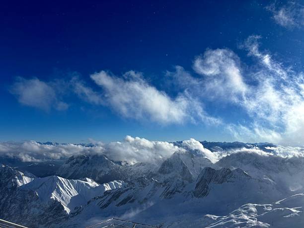 A panoramic view of the snow capped Wetterstein mountains covered by clouds from on top zugspitze in Garmisch-Partenkirchen Germany.