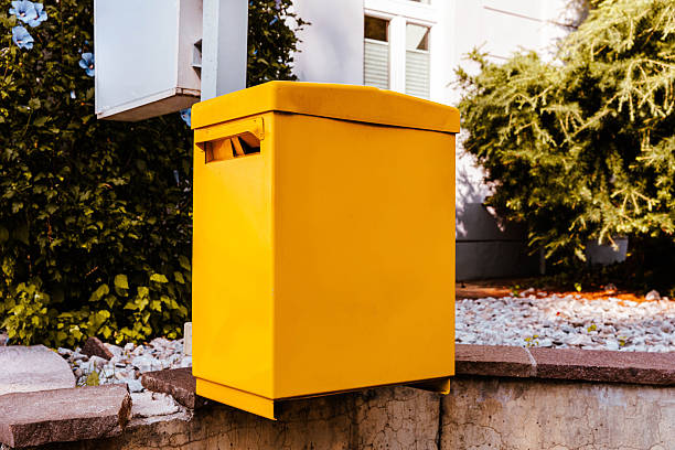Yellow mailbox on stone platform near green bush