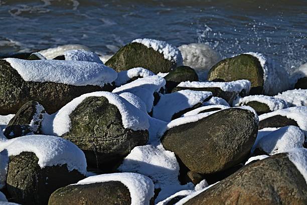 Snow-covered large stones on the Baltic Sea coast.