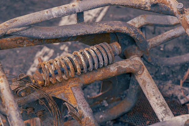 Grim aftermath of burned-down motorcycles left on a city street. The image displays the charred skeletons and melted remains of motorbikes amidst ash and debris.