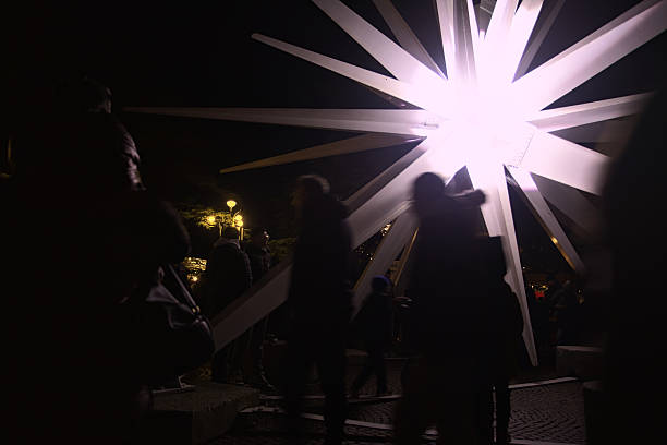 Verona, Italy - 8TH DECEMBER 2025 - Decorative light in the shape of a falling star next to the stalls of a Christmas market