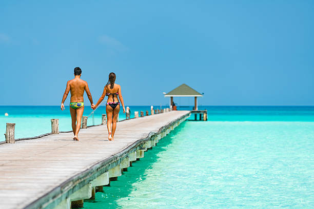 Dawn in the Maldives, and the sky above a wooden pier lights up with the first rays of sunlight.