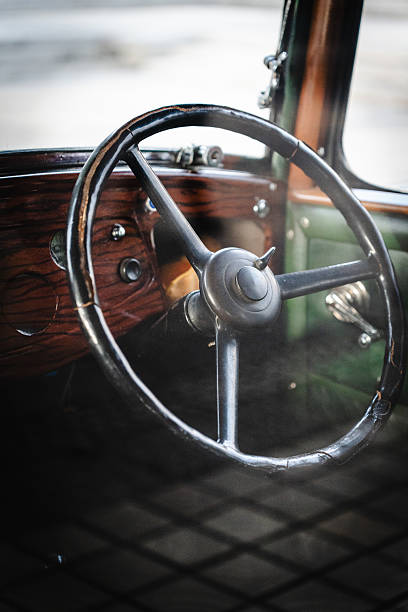 Focused shot of a vintage car interior featuring leather upholstery, steering wheel, and retro dashboard capturing elegance and classic automotive style.