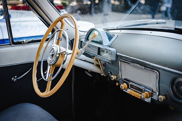 Detailed view of a retro car interior showing a polished wooden dashboard, chrome trim, textured leather seats, and vintage controls capturing timeless automotive craftsmanship.
