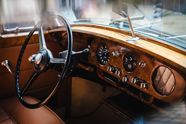 Focused shot of a vintage car cockpit highlighting leather seats, retro gear shifter, polished dashboard, and metallic accents reflecting classic car design.