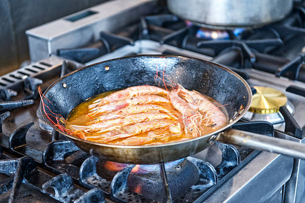 Langoustines cooking in pan on stove in spicy sauce