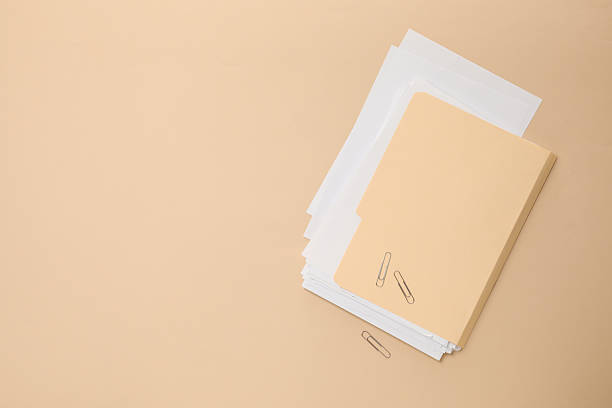 File folder with sheets and paper clips on beige background, flat lay. Space for text