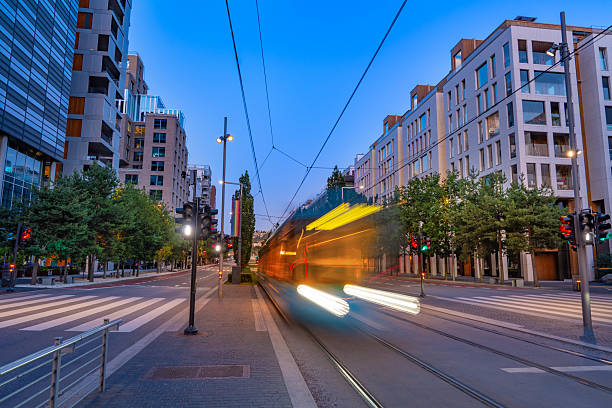 Blue city tram with motion blur passing along Dronning Eufemias gate in downtown Oslo at summer sunset